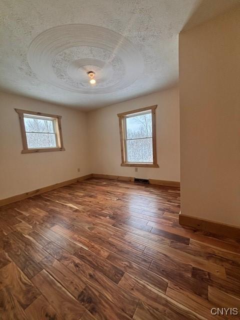 spare room with visible vents, dark wood finished floors, a textured ceiling, and baseboards