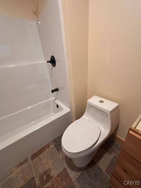 bathroom featuring  shower combination, stone finish floor, and toilet