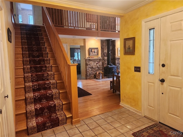 entrance foyer with a healthy amount of sunlight, light wood-type flooring, a wood stove, and ornamental molding