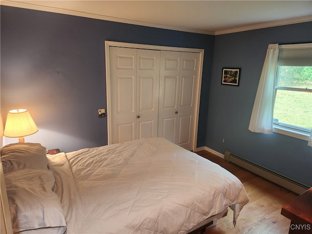 bedroom featuring a closet, crown molding, baseboard heating, and hardwood / wood-style flooring