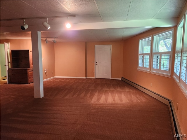 basement with carpet floors, plenty of natural light, rail lighting, and a baseboard radiator