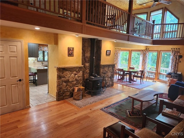 1666 Buffs Blf, Skaneateles, NY 13152 - living room with a high ceiling, a ceiling fan, a wood stove, healthy amount of natural light, and wood finished floors