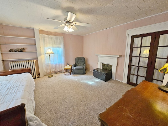 18 Wheeler St, Deposit, NY 13754 - carpeted bedroom with wooden walls, radiator heating unit, a fireplace, and ceiling fan