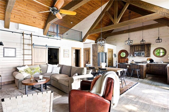 living room with high vaulted ceiling, ceiling fan, wood walls, a barn door, and wood ceiling