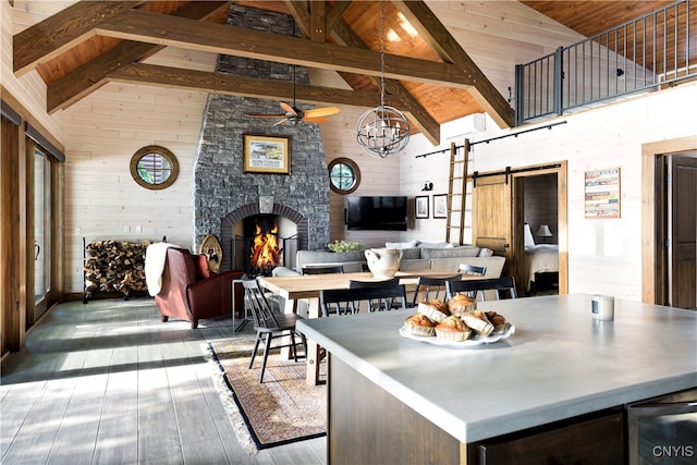 interior space with hardwood / wood-style floors, a barn door, high vaulted ceiling, a fireplace, and wood walls