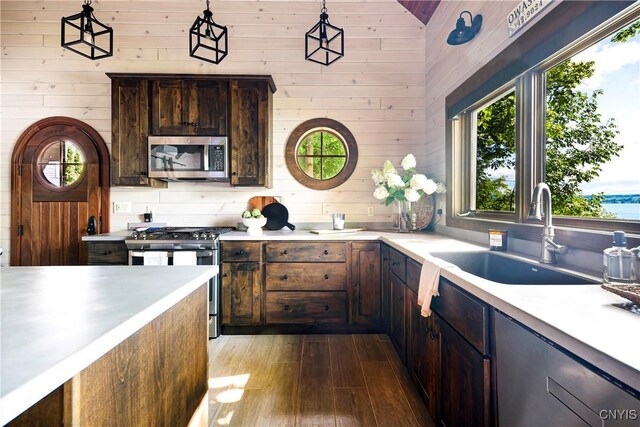 kitchen with appliances with stainless steel finishes, sink, light wood-type flooring, and wooden walls