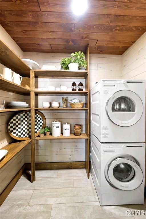 laundry area with wood walls, stacked washer and dryer, and wood ceiling