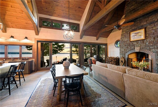 dining area featuring light hardwood / wood-style flooring, wooden ceiling, a water view, and high vaulted ceiling