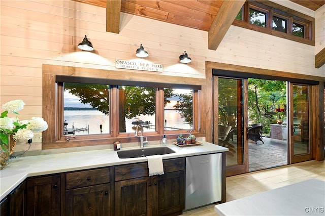 kitchen featuring dishwasher, beamed ceiling, a water view, light hardwood / wood-style flooring, and sink