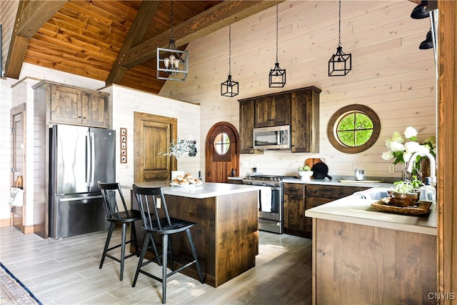 kitchen featuring wooden ceiling, appliances with stainless steel finishes, light hardwood / wood-style floors, wood walls, and a kitchen island