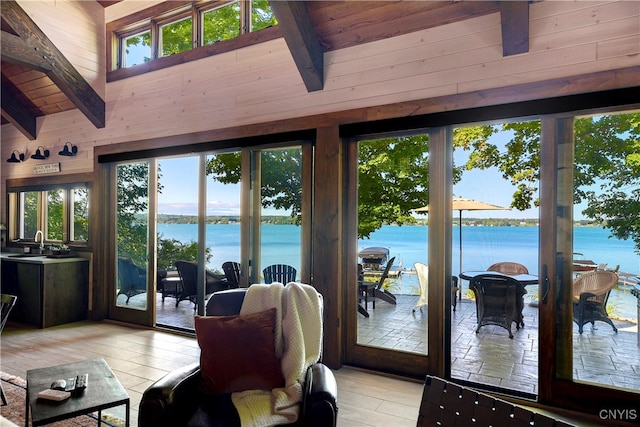 living room with a water view, light wood-type flooring, wood ceiling, and a healthy amount of sunlight