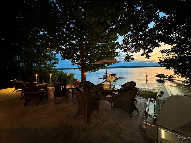 patio terrace at dusk featuring a water view