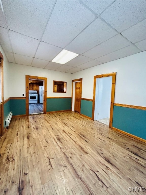 unfurnished room with a paneled ceiling, a baseboard heating unit, and hardwood / wood-style flooring