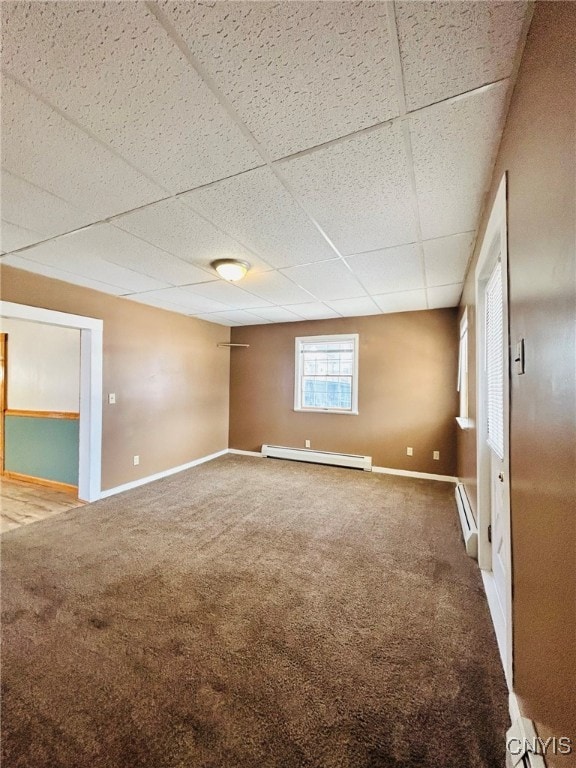 carpeted empty room featuring a baseboard radiator and a drop ceiling