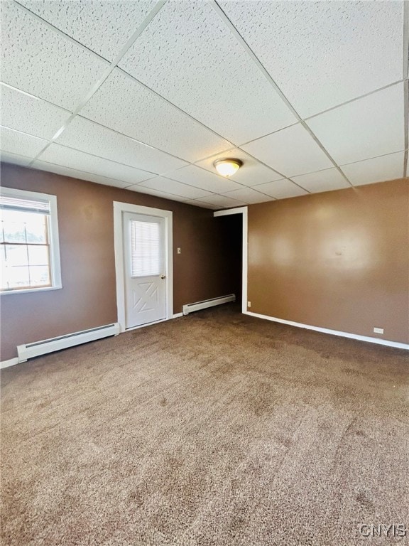 carpeted spare room featuring a wealth of natural light, a drop ceiling, and baseboard heating