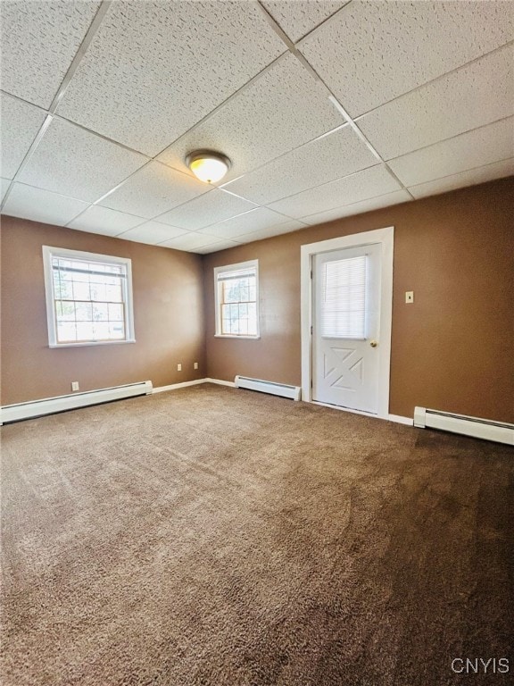 carpeted spare room featuring a baseboard radiator and a drop ceiling