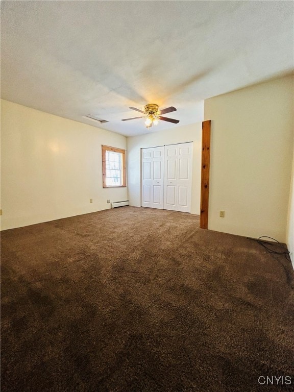 unfurnished bedroom with ceiling fan, baseboard heating, carpet floors, and a closet