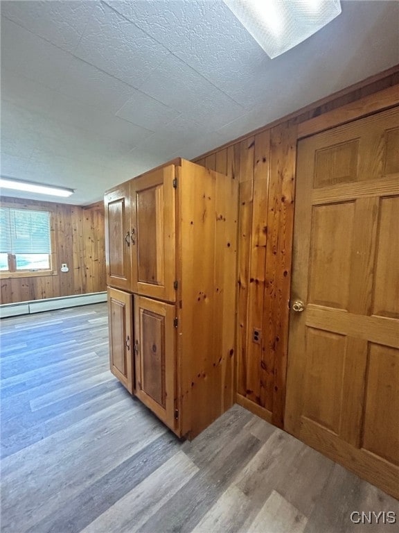 interior space with wood walls, light hardwood / wood-style flooring, and a baseboard radiator