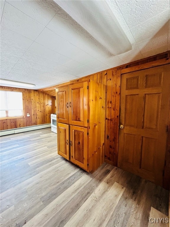 interior space featuring baseboard heating, wood walls, and light hardwood / wood-style floors