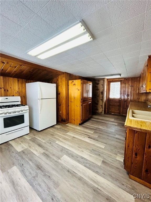 kitchen featuring white appliances, sink, and light hardwood / wood-style floors