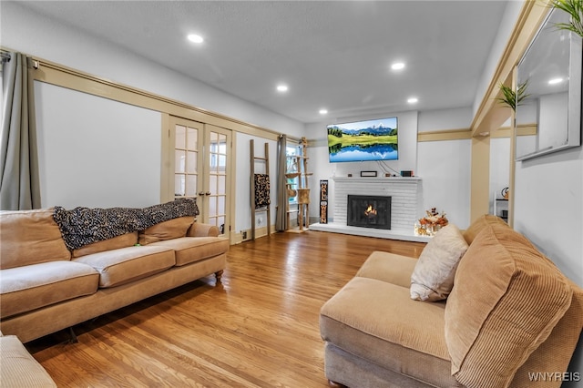 living room featuring french doors, a fireplace, and light hardwood / wood-style flooring