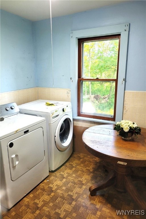 clothes washing area with dark parquet floors and washing machine and dryer