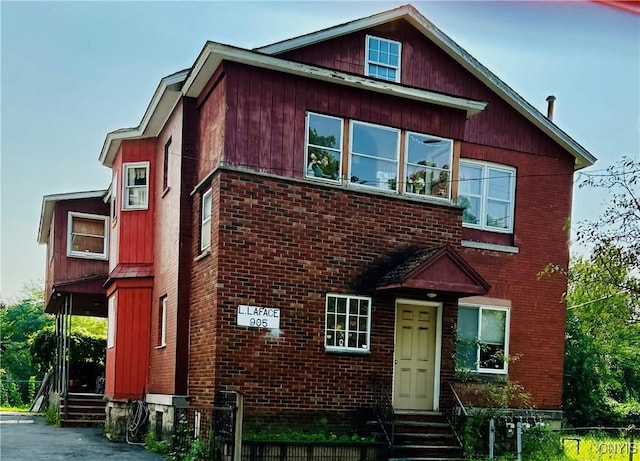 view of front facade with entry steps, brick siding, and fence