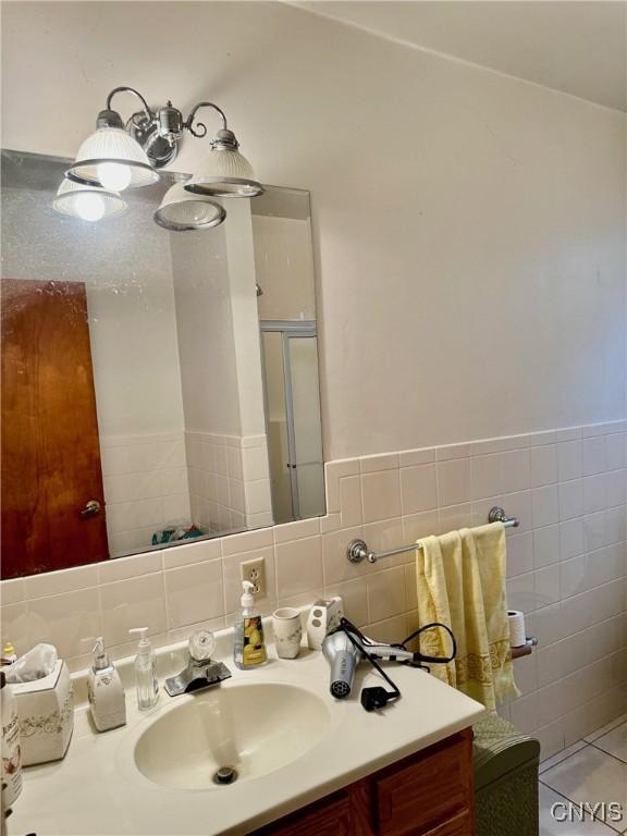 full bath featuring tile walls, a shower stall, and vanity