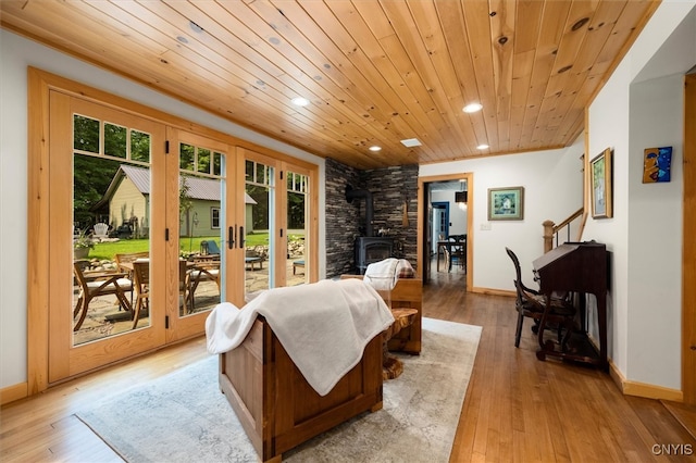 interior space with light wood-type flooring, a wood stove, and wooden ceiling