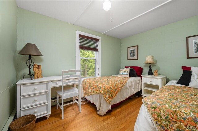 bedroom featuring a baseboard heating unit, light wood-type flooring, and ceiling fan