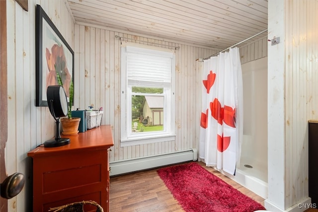 mudroom with wood walls, baseboard heating, and hardwood / wood-style flooring