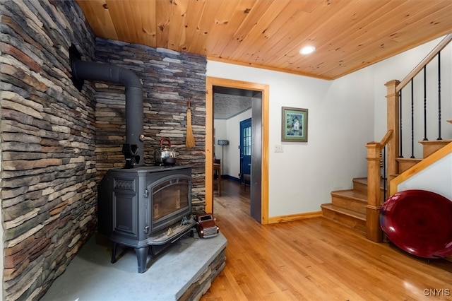 interior space with light hardwood / wood-style floors, crown molding, a wood stove, and wood ceiling