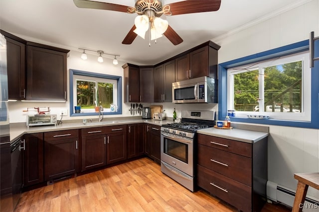 kitchen with stainless steel appliances, sink, light wood-type flooring, a wealth of natural light, and baseboard heating