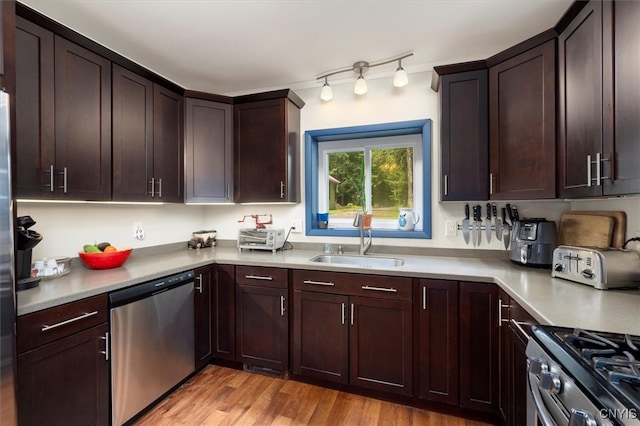 kitchen featuring stainless steel appliances, dark brown cabinetry, sink, and light hardwood / wood-style flooring