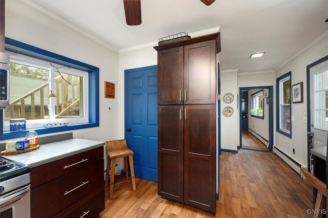 kitchen featuring appliances with stainless steel finishes, baseboard heating, crown molding, and hardwood / wood-style flooring