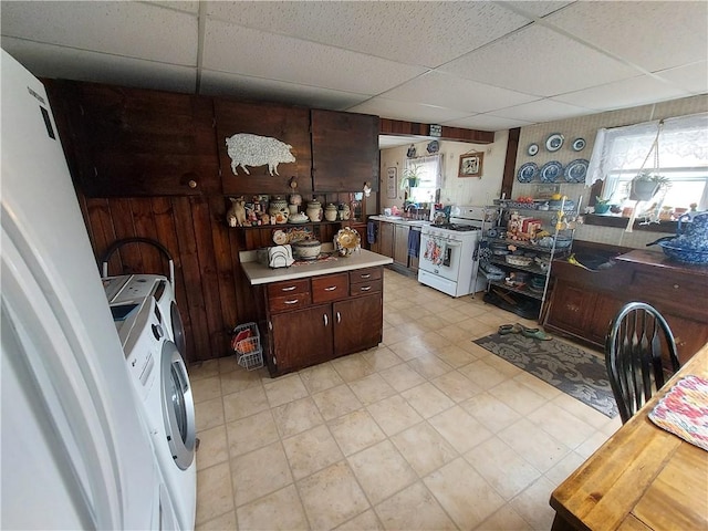 kitchen with dark brown cabinets, a paneled ceiling, a healthy amount of sunlight, and white range with gas stovetop