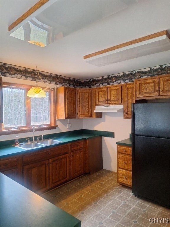 kitchen featuring black fridge, hanging light fixtures, and sink