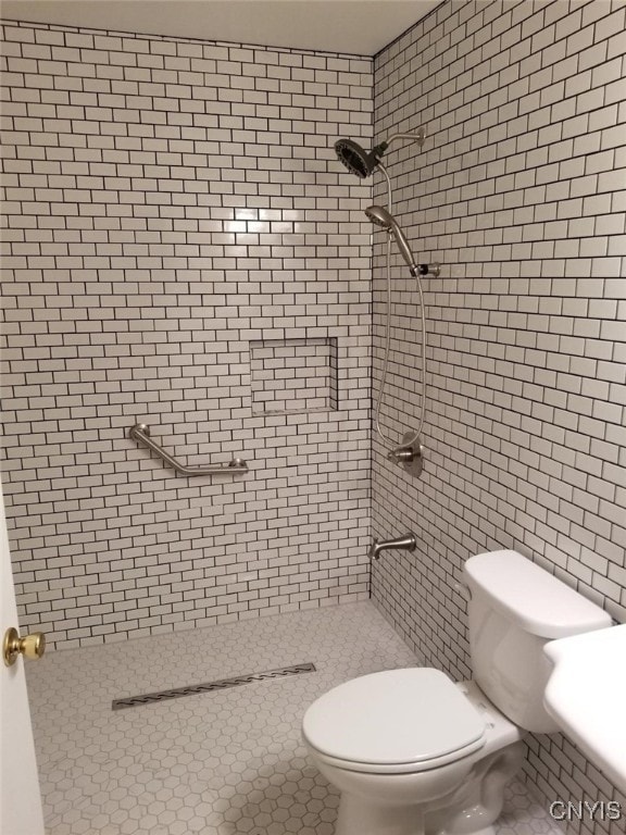 bathroom featuring tiled shower, tile patterned floors, and toilet