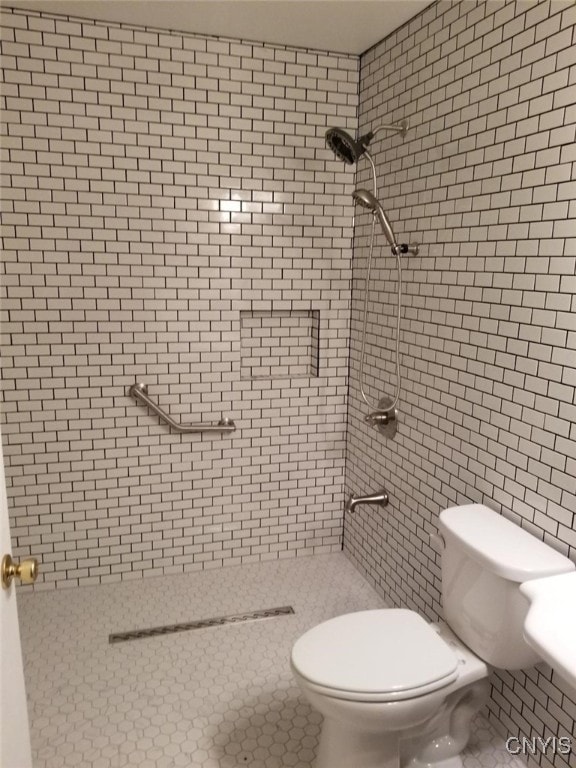 bathroom with a tile shower and toilet