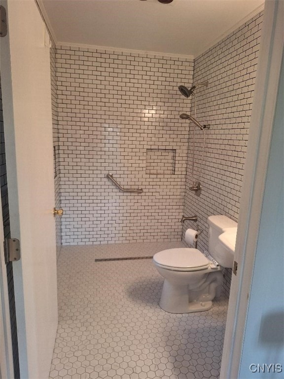 bathroom with tiled shower, tile patterned floors, toilet, and crown molding