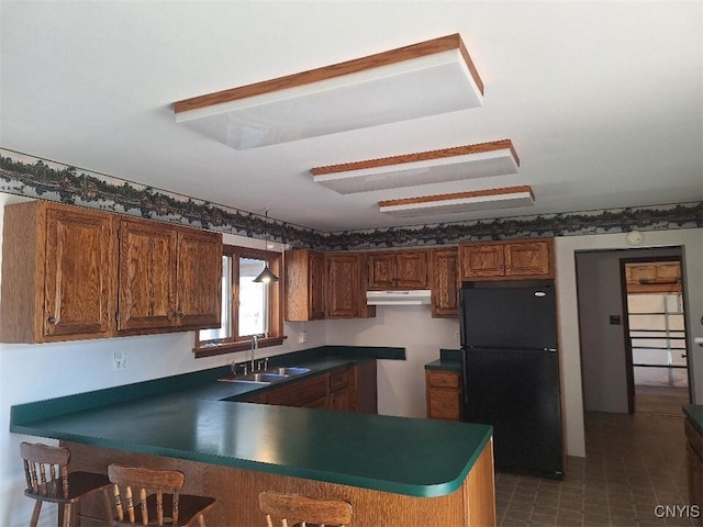 kitchen featuring black refrigerator, kitchen peninsula, and sink