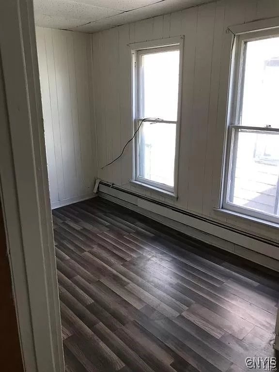 empty room featuring plenty of natural light, hardwood / wood-style flooring, and baseboard heating