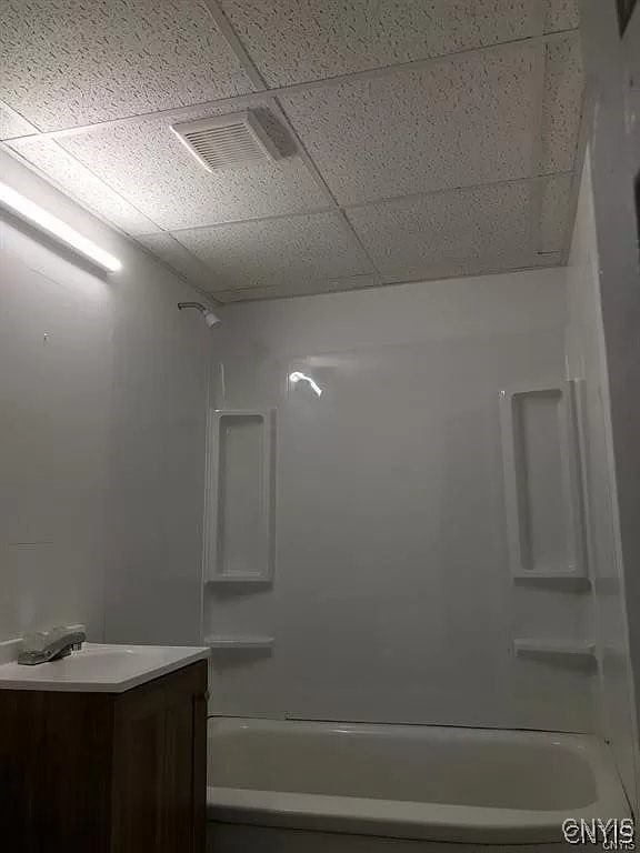 bathroom featuring shower / bathtub combination, a paneled ceiling, and vanity