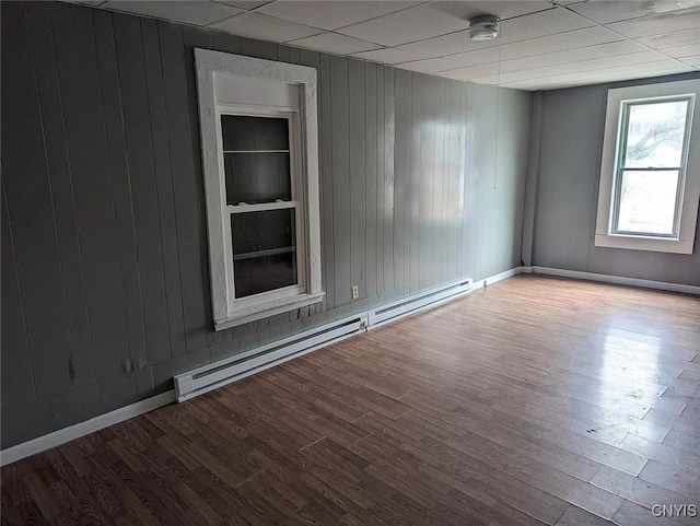 spare room featuring a drop ceiling, a baseboard heating unit, and wood-type flooring