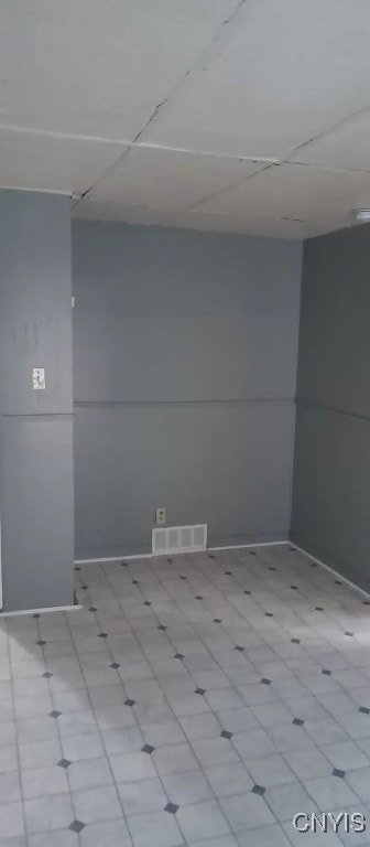 spare room with a drop ceiling and light tile patterned floors