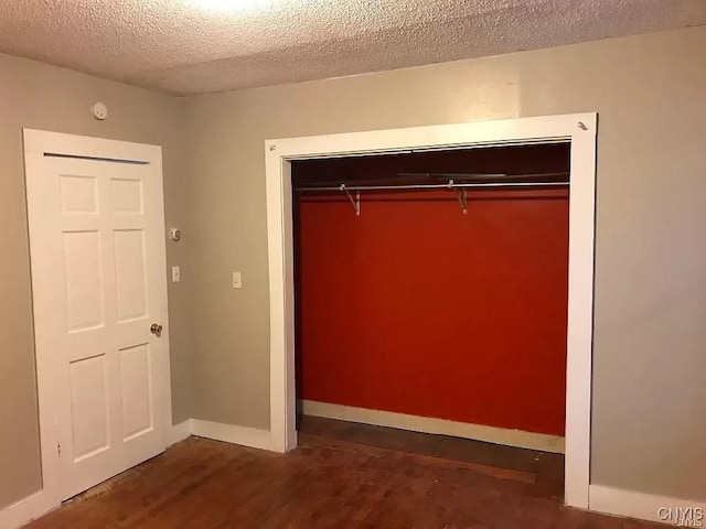 unfurnished bedroom featuring a textured ceiling, hardwood / wood-style flooring, and a closet