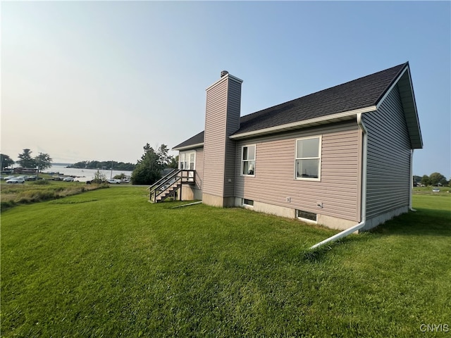 rear view of property featuring a lawn and a water view