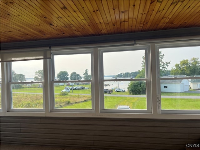 unfurnished sunroom with a healthy amount of sunlight, wooden ceiling, and a water view