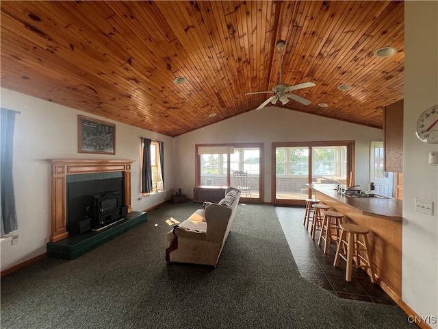 carpeted living room with ceiling fan, a tiled fireplace, wooden ceiling, and lofted ceiling