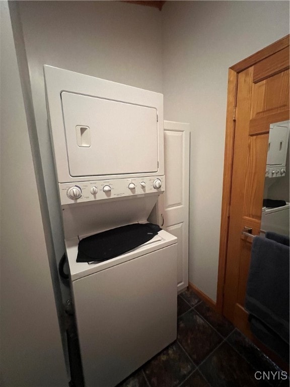 washroom with stacked washer / dryer and dark tile patterned flooring